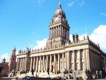 Large, rectangular, extremely ornate, marble building with many columns and other decorative details, including a columned tower on the roof.