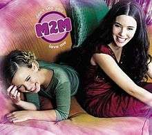 Two young teen girls on a purple couch, one lying prone and one sitting. Both are smiling.