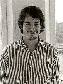 A black and white photo of young man with dark hair and a mustache