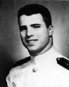 Formal portrait of young, dark-haired man in white naval uniform