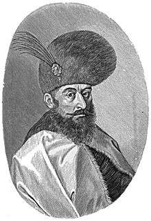 Bearded man with mustache, wearing large round hat with feather