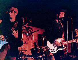 Two men playing electric guitar in a dimmed lightning