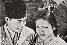 A man and woman standing close together; both are in their mid-20s.