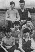 Six young boys holding hurleys in a field