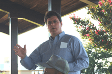 A photograph of a middle-aged man speaking to a crowd behind the camera.