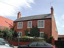 An old house of brick construction. Ivy is growing up its walls.