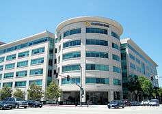 Modern white-clad six story building in bright sunshine.