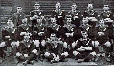 A team of rugby players assembled in three rows posing for a team photo