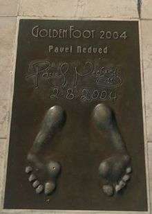 A golden cast of Nedved's footprints. His signature and the date are recorded at the top of the image.