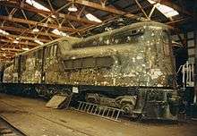 An unpainted, dirty-looking locomotive in a warehouse.