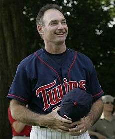 Baseball player in a blue and red "Twins" jersey, holding his cap