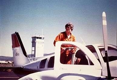  Photo of Mary Barr standing on the wing of her transport plane, 1975