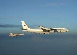 Air-to-air view of four-engined jet transport refuelling fighter plane