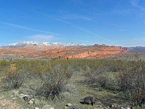 A photo of the Red Cliffs with snow-capped Pine Valley Mountains in the background