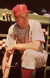 A man in a white baseball uniform with "Phillies" in red across the chest and a red baseball cap with a white "P" on the front