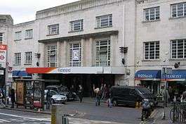 A grey building with a rectangular, white sign reading "Richmond" in dark blue letters all under a light blue sky with white clouds