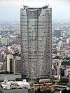 Aerial view of a gray, oval-shaped high-rise lined with rows of windows; the facade is bisected by a smaller midsection