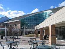 A circular opening to a building with chairs and tables out in front of the building