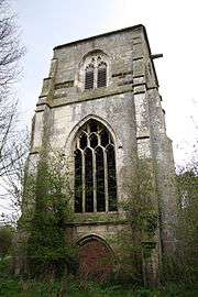 A tower with three stages; in the bottom stage is a door, in the middle stage is a large window with tracery, and in the top stage is a two-light louvred bell opening