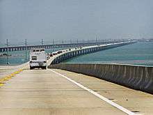 A view of a long bridge over water: a number of cars are visible in the left hand lane