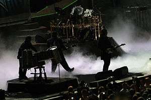 A rock band silhouetted on a dark stage with white fog on the stage floor