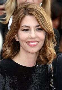 Portrait a brown-haired female with a black dress.