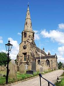 A stone church with a west steeple consisting of a square tower, an octagonal drum and spire, the latter with lucarnes.