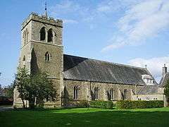 A stone church with a west tower surmounted by battlements and a small spirelet