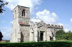 A stone church seen from the southwest, with a tower on the left; the porch and body of the church are battlemented