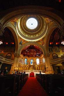 Very wide angle which shows all the major internal spaces of the church, the nave, the dome supported on large arches, a transept to either side and the chancel central to the image, which shows the way the gold mosaics gleam in contrast to the dark shadows.