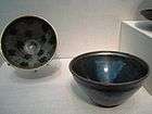 Two small polished black bowls. One has a large blue streak in it, the other has a polka-dot pattern on the inside consisting of black spots on a dark grey background. All of the coloring is created by features of the stone, rather than paint.