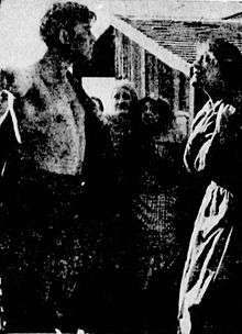 A partially bare-chested man faces a defiant woman in an old hard to see photograph