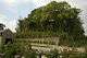 A nursery with a woodend sheds with a breeze block wall, behind which is an earthern mound covered with trees