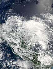 Satellite image of a large, disorganized mass of clouds near a landmass.