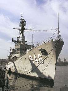 Grey warship looking up from the box end taken from the quay-side against a blue sky