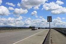 A highway shield on a concrete freeway bridge