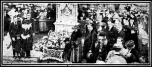 A large white grave is in the centre, surrounded on either side by crowds