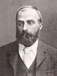 A middle-aged bearded man wearing a tie, waistcoat and jacket.