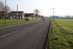 Quiet road with housing on one side and fields on the other